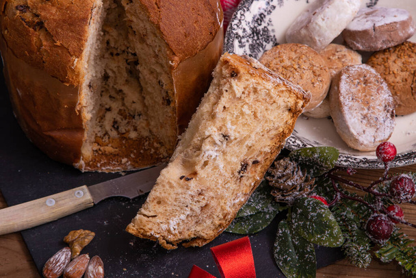 portion of panettone cut on the table with christmas decorations - Photo, Image