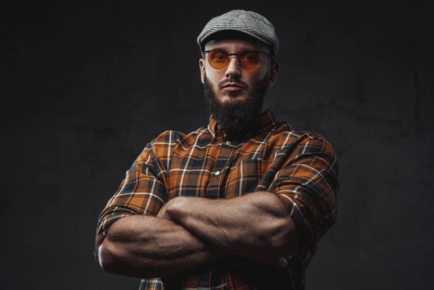 Stylish strong guy with cap and sunglasses poses with crossed arms - Photo, Image