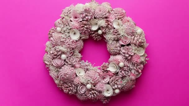 Στεφάνι Χριστουγέννων φτιαγμένο με λουλούδια, πεύκα και φύλλα που απομονώνονται σε ροζ φόντο - Πλάνα, βίντεο