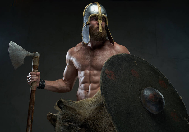 Nordic warrior with axe and shield in studio with spotlight - Photo, Image