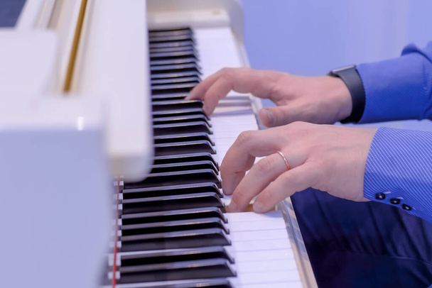 Człowiek ręce gra na białym fortepianie na koncercie - widok z boku - Zdjęcie, obraz