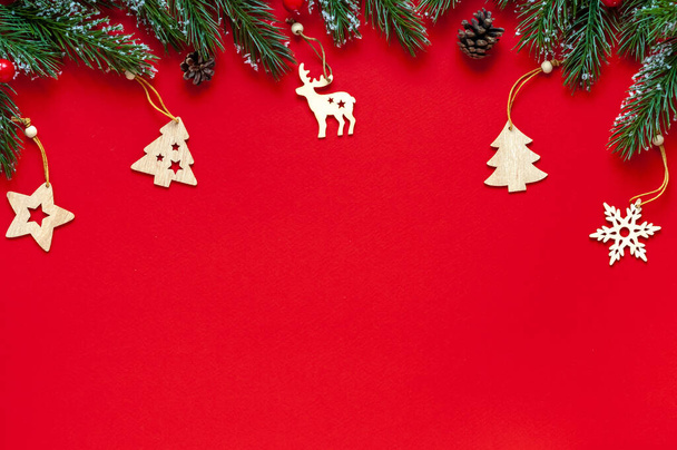 Branches de sapin, jouets de Noël en bois sur fond rouge.Fond de Noël ou Nouvel An avec placement de texte - Photo, image