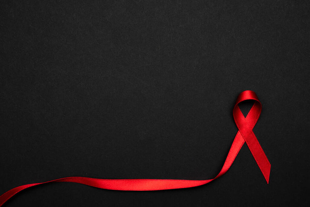 Поддержка Hiv. Символ красной ленточки в мировом дне на черном фоне. Осведомленность и рак. Месяц старения - Фото, изображение
