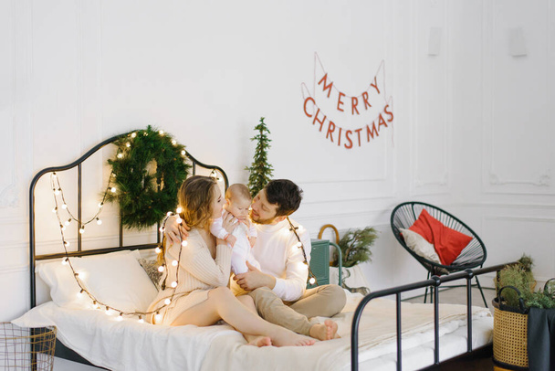 Happy family with little son at christmas decorated home in bed - Foto, imagen