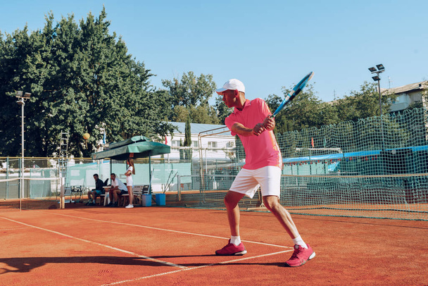 Middle-aged man playing tennis on outdoor tennis filed - Foto, imagen
