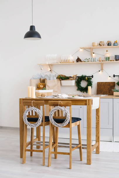 Año nuevo y Navidad. Cocina escandinava festiva en decoraciones navideñas. Velas, ramas de abeto, soportes de madera, mesa. - Foto, imagen