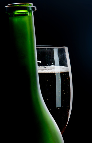 Glass of champagne behind a bottle - 写真・画像