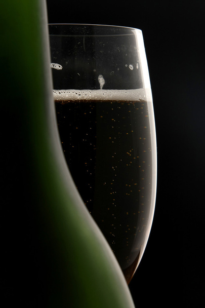 Glass of champagne behind a bottle - 写真・画像