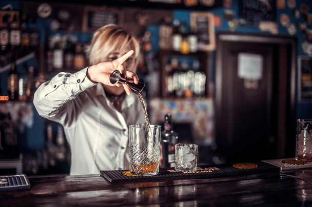 Portrét ženy barman umístí závěrečné doteky na nápoj u pultu baru - Fotografie, Obrázek