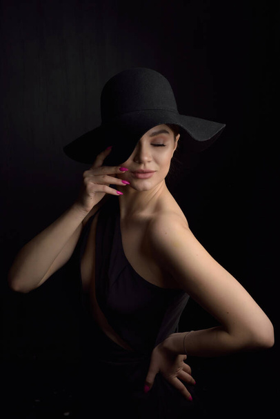 帽子の美しい女性。レトロなファッション。暗い背景. - 写真・画像