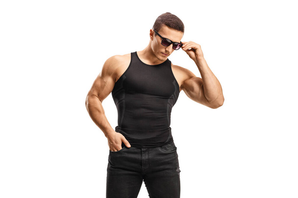 Подходящий молодой человек в черной рубашке без рукавов и солнечных очках изолированы на белом фоне - Фото, изображение
