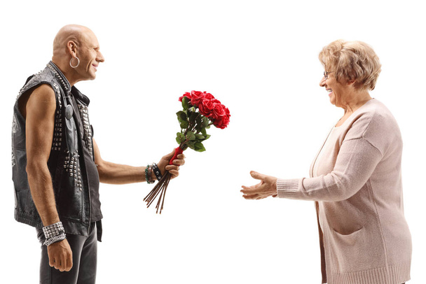 Bald punk giving a bouquet of roses to an elderly woman isolated on white background - Photo, image