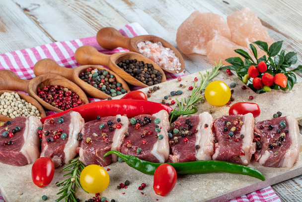 Du kebab cru. Steak d'agneau cru servi sur une planche à découper en pierre avec sel de mer et flocons de poivre, romarin et menthe. - Photo, image