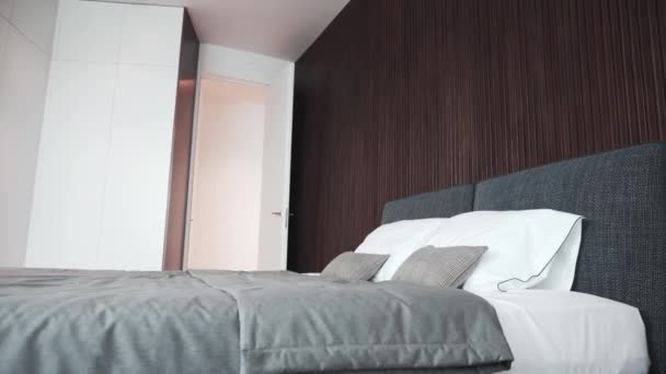 美しい白い枕とグレーの毛布、背景に木製の壁で構成されたモダンなダブルベッド。高級ベッドルームインテリア、ホテルサービスの概念. - 映像、動画