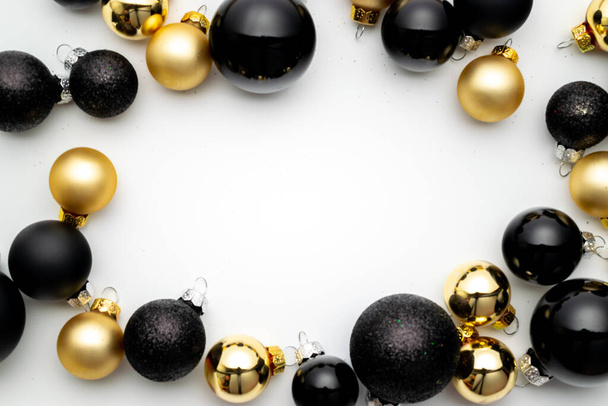 Подарочная коробка. Черные безделушки, золотые шарики в рождественском украшении на белом фоне для поздравительной открытки. Зимняя праздничная композиция с копировальным пространством. - Фото, изображение