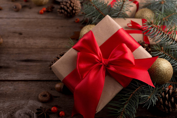 Bezár up Ajándék doboz piros selyem íj között karácsonyi dekorációk egy fa asztalon. Boldog karácsonyt és boldog új évet háttér. - Fotó, kép