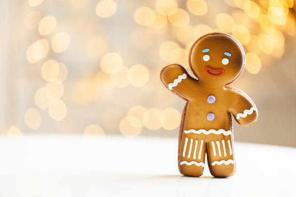 Gingerbread man cookie on the blurred Christmas lights background. Warm bokeh lights. Macro shot. New Year and winter holidays background. Winter coffee time - Foto, Imagen