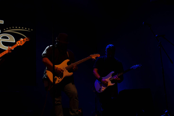 Siluetas Pareja de jóvenes guitarristas tocando las guitarras eléctricas en el escenario en la Ciudad de México - Foto, imagen