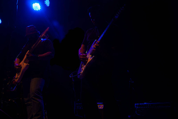 Siluetas Pareja de jóvenes guitarristas tocando las guitarras eléctricas en el escenario en la Ciudad de México - Foto, Imagen