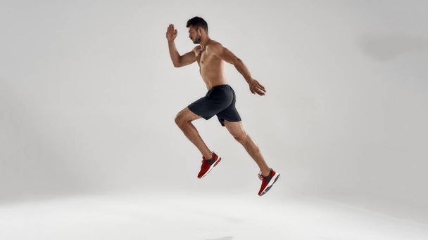 Young handsome caucasian professional male runner jumping - 写真・画像