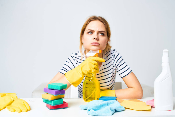 woman sitting at the table detergent rags sponges home care interior light background - Photo, Image