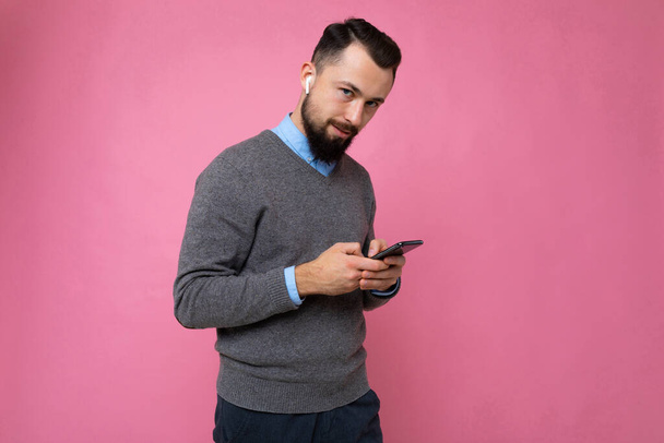 ピンクの背景にハンサムな男は携帯電話でメッセージを送信します。 - 写真・画像