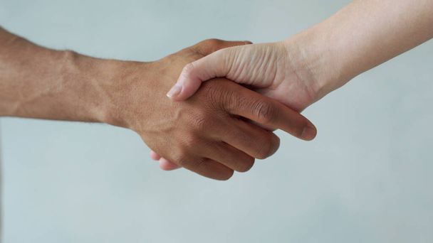Valkoinen ja musta käsi yhdistää. Rasismin vastainen. Lopettakaa rasismi, kaikki ihmiset ovat tasa-arvoisia. Kansojen ystävyys. Mustien elämillä on väliä - Valokuva, kuva