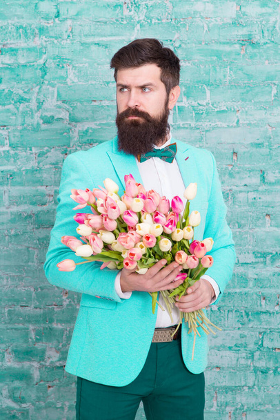 We take flowers personally. Spring gift. Bearded man hipster with flowers. Love. international holiday. Womens day. March 8. Bearded man with tulip spring bouquet. Spring time. enjoying spring - Fotografie, Obrázek