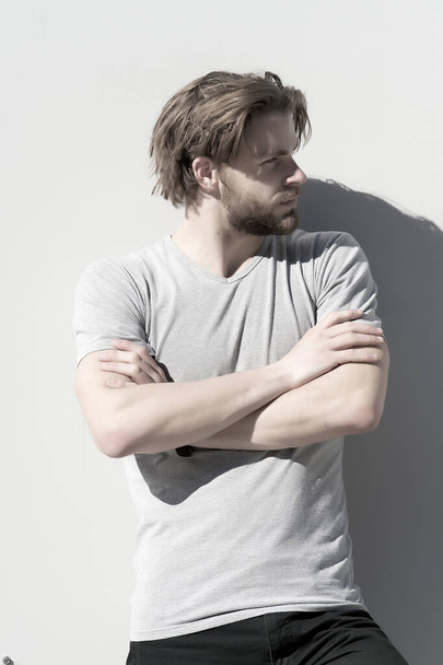 Man in tshirt pose with folded hands on grey wall - 写真・画像