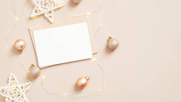 Christmas card mockup on pastel beige background with balls and stars decoration. Flat lay, top view. Minimal style - Photo, Image