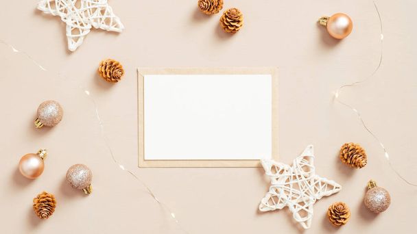 Blank paper card and envelope with balls and stars, Christmas decorations on pastel beige background. Flat lay, top view. Christmas letter concept. - Fotoğraf, Görsel