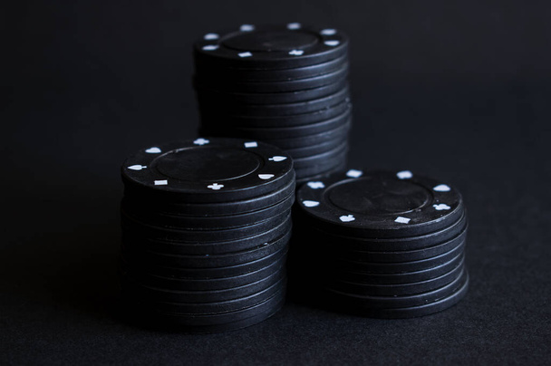 tři hromady černých pokerových žetonů na černém pozadí - Fotografie, Obrázek