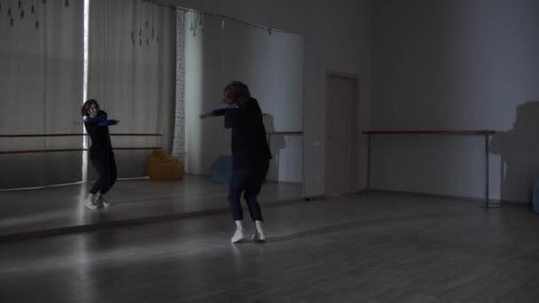 Пристрасть до сучасного танцю, дівчина танцює нові рухи з дзеркалом для її сучасного танцю в танцювальній школі
. - Кадри, відео