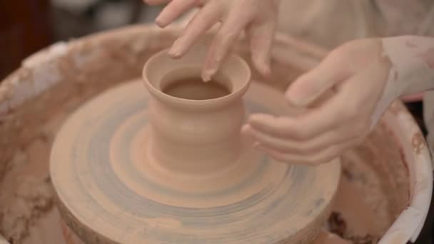 A potter is using his finger to shape a clay pot rotating on a potters wheel - Footage, Video
