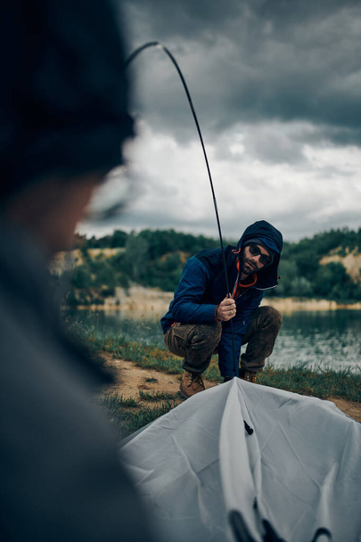 Two men adjusting tent on camping trip. - Foto, Imagen