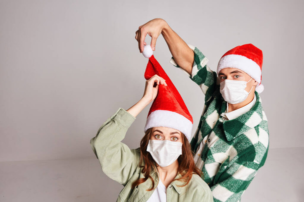 Young couple of Christmas hats Christmas winter fun medical masks on face - Photo, Image