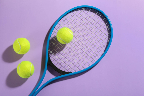 Tennis racket and balls on violet background, flat lay. Sports equipment - Фото, изображение