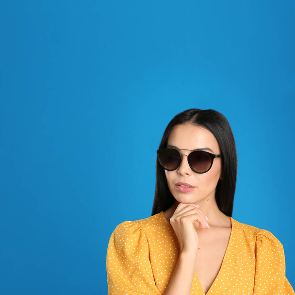 Beautiful woman wearing sunglasses on blue background. Space for text - Valokuva, kuva