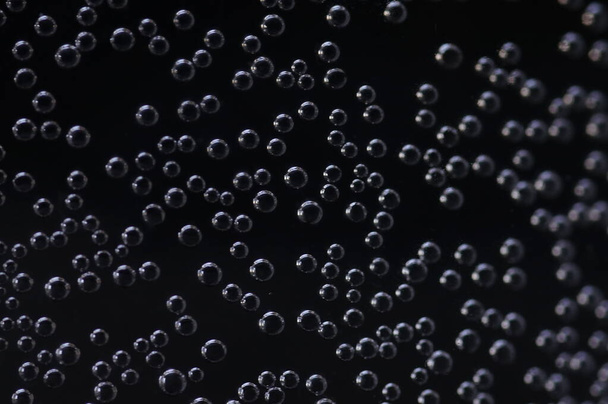 Burbujas de aire en un vaso de agua en una habitación oscura. - Foto, imagen