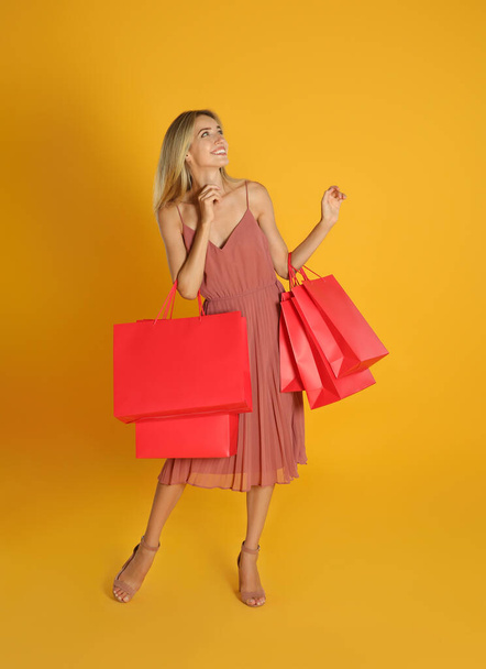 Happy young woman with shopping bags on yellow background. Black Friday Sale - Foto, immagini