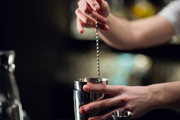 Ein erfahrener Barkeeper bereitet einen alkoholischen Cocktail zu. Kein Gesicht, Nahaufnahme, Kopierraum. - Foto, Bild