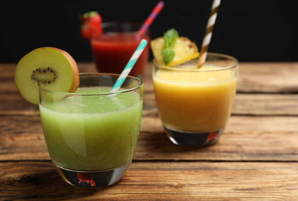 Delicious colorful juices in glasses on wooden table, closeup - Фото, изображение