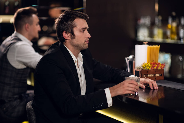 Egy fiatalember koktélt iszik a bárban, kommunikál a csapossal. - Fotó, kép