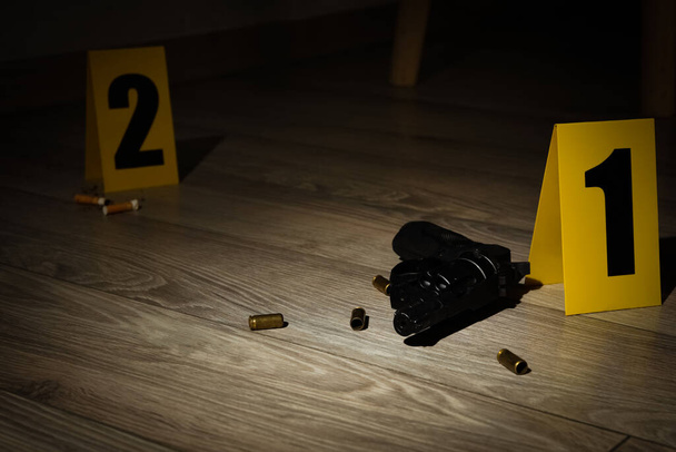 Gun and shell casings on wooden floor at crime scene - 写真・画像