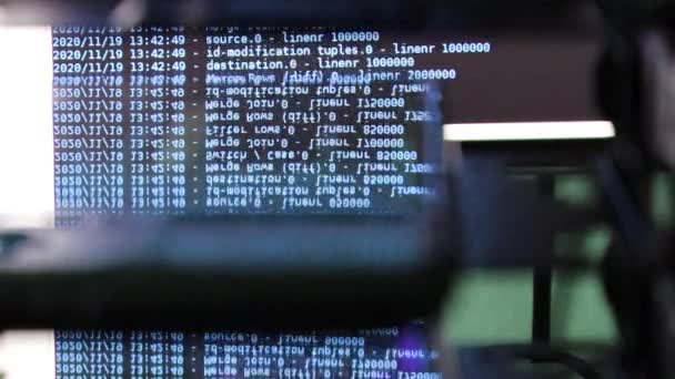 ブラックモニター上で動く青いコンピュータソフトウェアコードはガラスに反射しています。概要ラックサーバベースで処理中のコンピュータのハッキング、動的テキストの実行とPC画面上で流れる. - 映像、動画