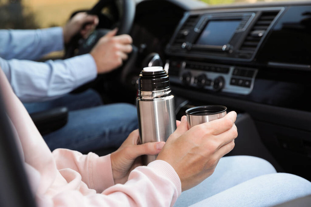 Woman with thermos on passenger seat of car, closeup - Photo, Image