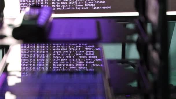 Softwarový kód fialového počítače pohybující se na černém monitoru odrážejícím se na skle. Abstraktní hackování počítače v procesu se základnou rack serveru, dynamický text běží a teče na obrazovce PC. - Záběry, video