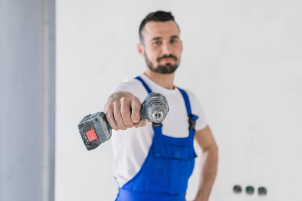 Bearded handyman shows a drill to the camera - Photo, Image