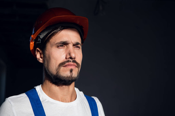 Young workman puts orange hard hat on his head - Photo, Image