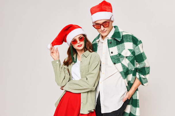 Man and woman in sunglasses Christmas hat hugs holiday Studio - Фото, изображение